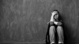 Girl in Grief holds her head sitting on the floor