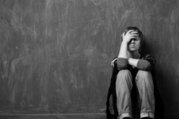 Girl in Grief holds her head sitting on the floor